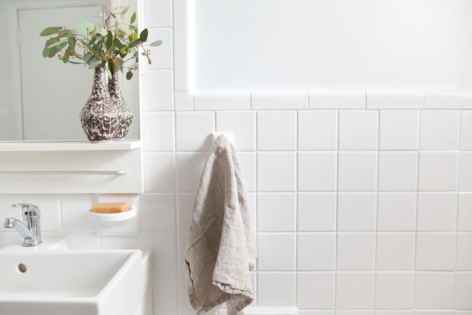 Hexagon gray and white wall tile above a wood countertop with a ceramic pitcher and plants